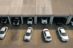 Aerial view of multiple busy automotive garages in a row with vehicles parked outside and mechanics working, representing Oman’s vibrant automotive service sector.